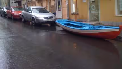 A image of a boat placed in a parking space on a street